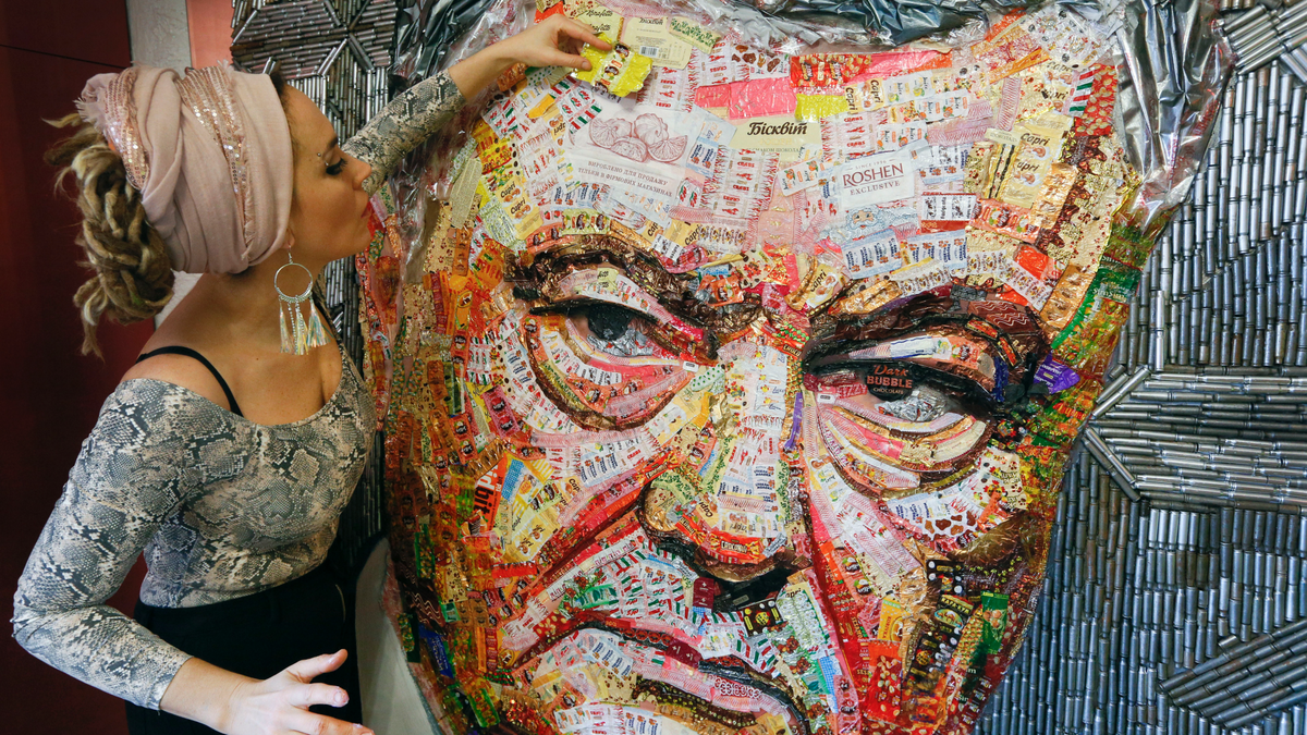 Ukrainian artist Dasha Marchenko adds a chocolate wrapper to her portrait of Ukraine's President and chocolate tycoon Petro Poroshenko at her studio in Kiev, Ukraine, Thursday, March 28, 2019. (AP Photo/Efrem Lukatsky)