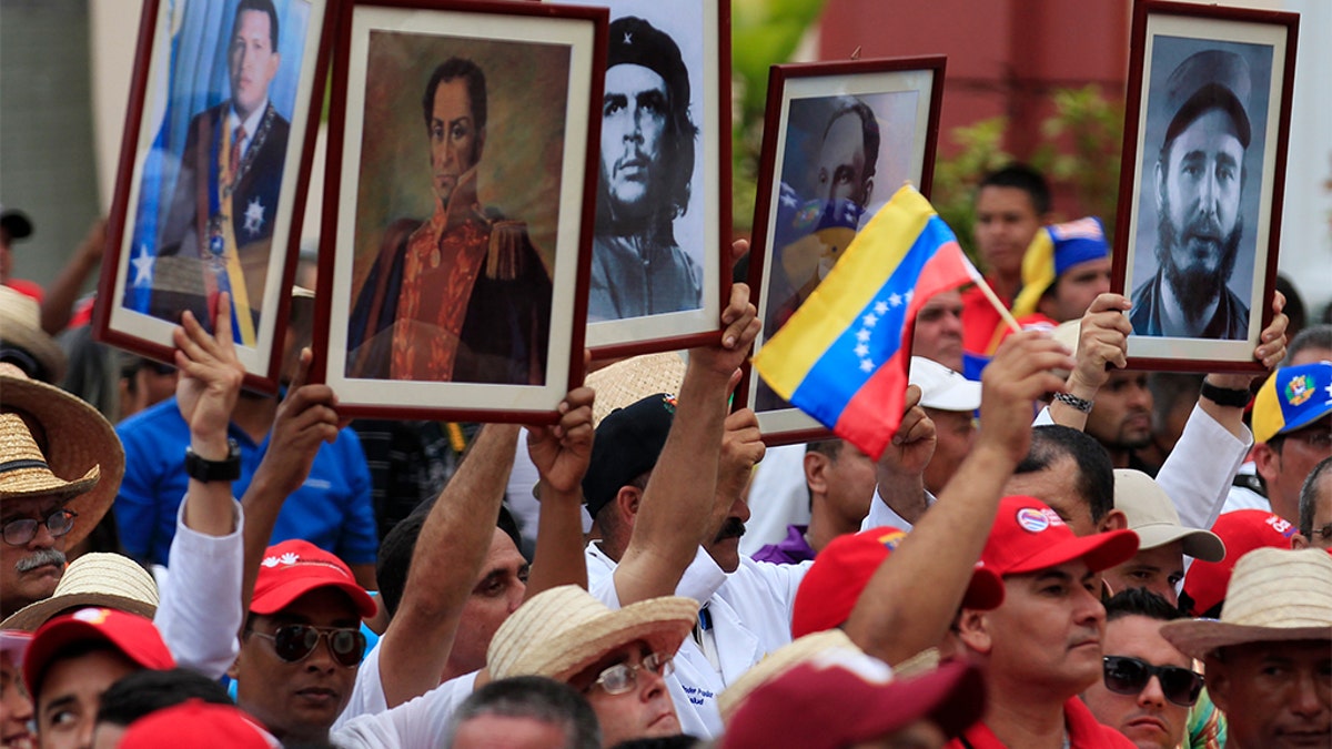 Cuban doctors hold up framed pictures (L-R) of late President Hugo Chavez, Venezuela's National hero Simon Bolivar, Ernesto 'Che' Guevara, Cuban national hero Jose Marti and Fidel Castro during a march of farmers in support of Venezuela's President Nicolas Maduro in Caracas February 26, 2014.  REUTERS/Tomas Bravo