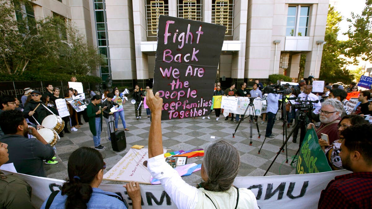 FILE - In this June 20, 2018, file photo, protesters demonstrate outside the federal courthouse in Sacramento, Calif., where a judge heard arguments over the U.S. Justice Department's request to block three California laws that extend protections to people in the country illegally. The Justice Department told The Associated Press at the end of February 2019 that 28 jurisdictions, including Sacramento, that were targeted in 2017 over what it considered "sanctuary" policies have been cleared for law enforcement grant funding. (AP Photo/Rich Pedroncelli, File)