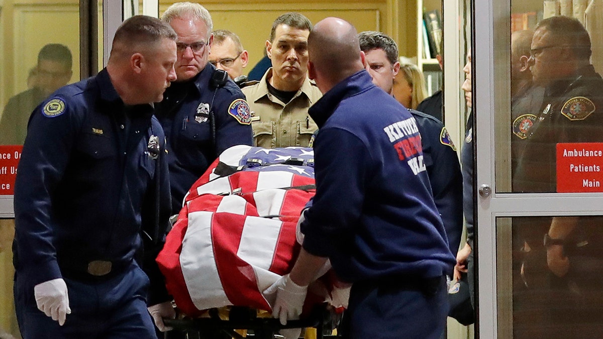 The body of Kittitas County sheriff's deputy Ryan Thompson is draped with a U.S. flag as it is carried out of Kittitas Valley Healthcare Hospital in the early morning hours of Wednesday, March 20 in Ellensburg, Wash. (Associated Press)