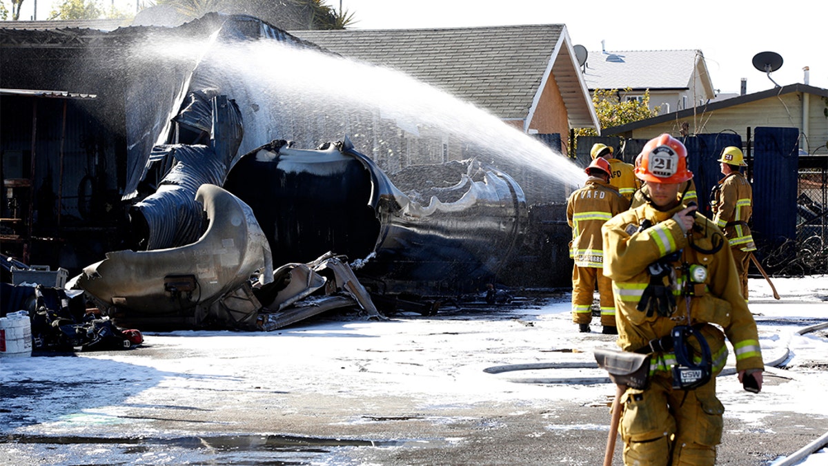 Firefighters dousing the fire which sent up a huge plume of smoke near Los Angeles on Sunday.