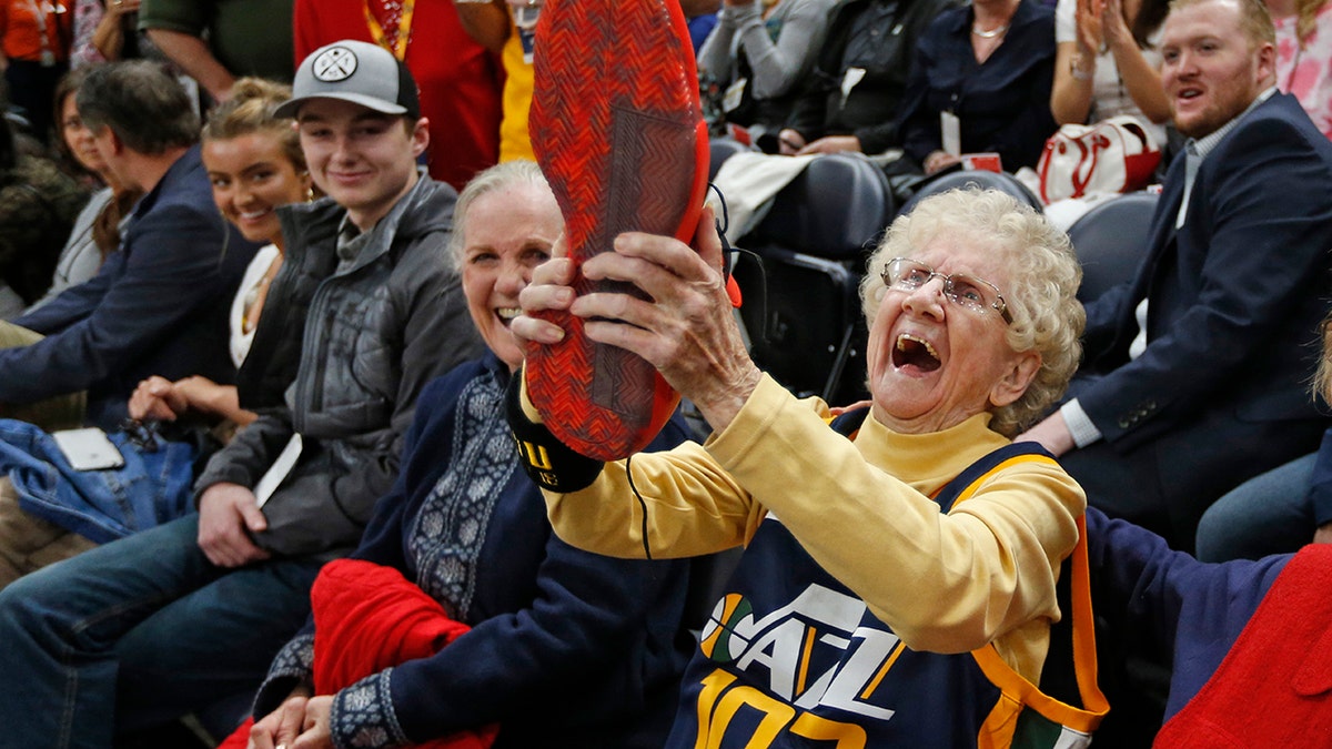 Roberta Morgan, 102, celebrates after Utah Jazz guard Donovan Mitchell handed his basketball shoe to her after he warmed up for the team's NBA basketball game against the Milwaukee Bucks on Saturday, March 2, 2019, in Salt Lake City.