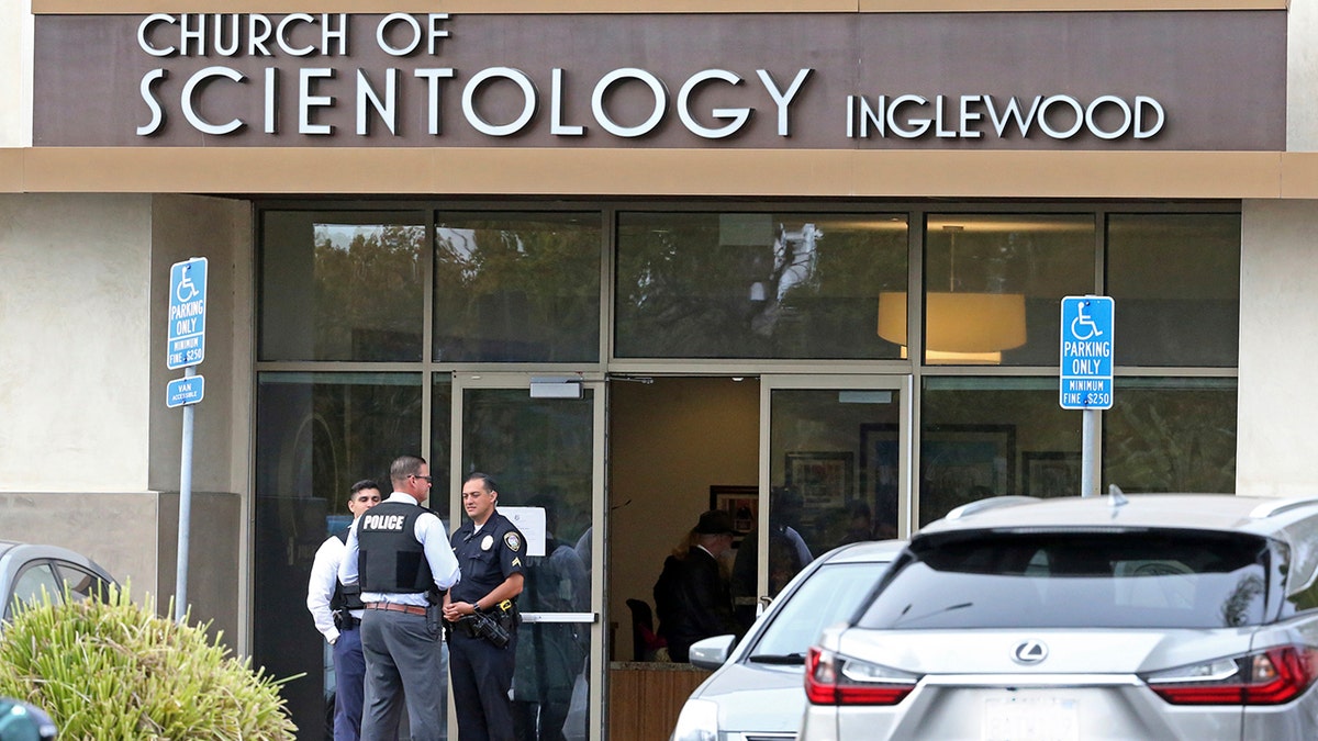Police stand by outside and investigators work inside the entrance to the Church of Scientology in Inglewood, Calif., on Wednesday. (Associated Press)