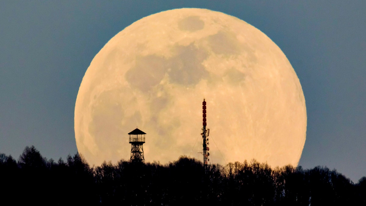 A lookout tower, left, and the broadcast tower of Antenna Hungaria at the top of Karancs mountain are backdropped by the rising moon as seen from the vicinity of Karancskeszi village, 128 kms northeast of Budapest, Hungary, Wednesday, March 20, 2019.