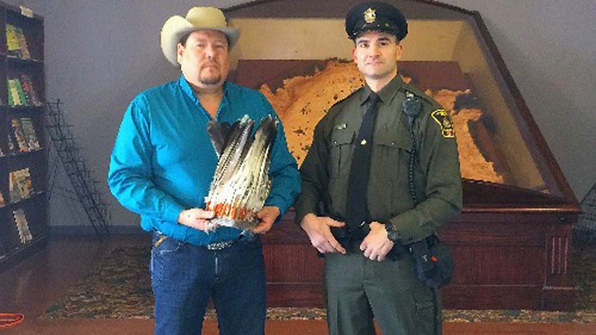 Kent Ayoungman of the Blackfoot Federation, (l), holds Blackfoot headdress that was at a thrift store in near Calgary. Alberta Fish and Wildlife officer Philip Maraso (r.) seized the headdress investigating a tip to a poaching hotline.