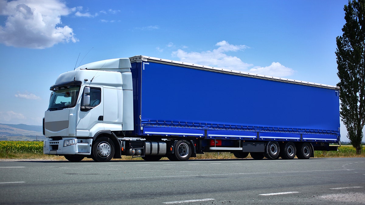 White semi truck and blue trailer on the road.