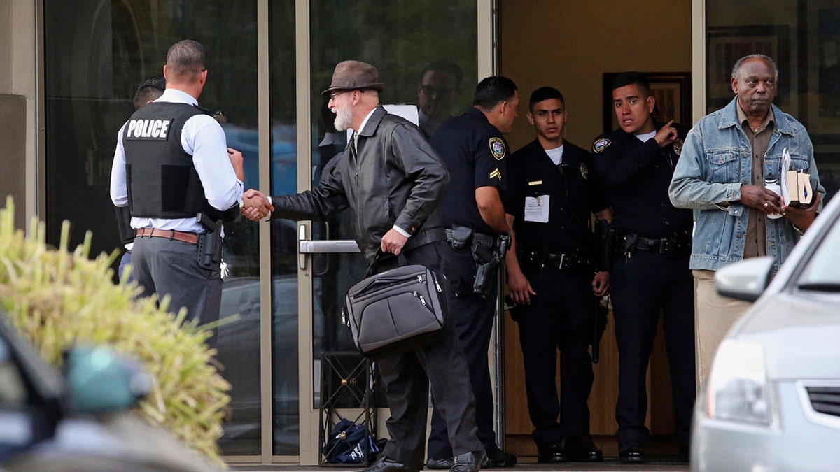 An unidentified man who had been inside the building shakes officers' hands outside the Church of Scientology in Inglewood, Calif., on Wednesday. (Associated Press)