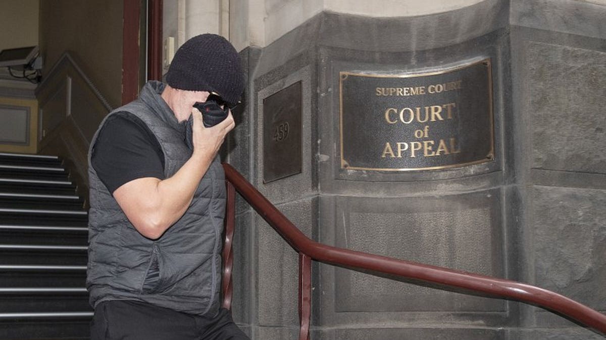 Workplace bullying claimant David Hingst covers his face as he leaves the Court of Appeal in Melbourne, Australia Friday, March 29, 2019. The Australian appeals court on Friday dismissed a bullying case brought by the engineer Hingst who accused his former supervisor of repeatedly breaking wind toward him.