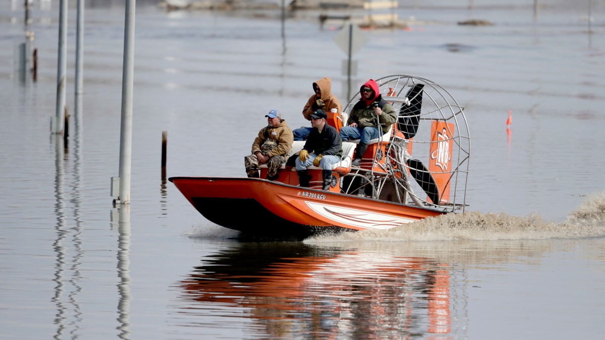 Gabe Schmidt, owner of Liquid Trucking, back right, travels by air boat with Glenn Wyles, top left, Mitch Snyder, bottom right, and Juan Jacobo, bottom left, as they survey damage from the flood waters of the Platte River, in Plattsmouth, Neb., Sunday, March 17, 2019. (AP Photo/Nati Harnik)