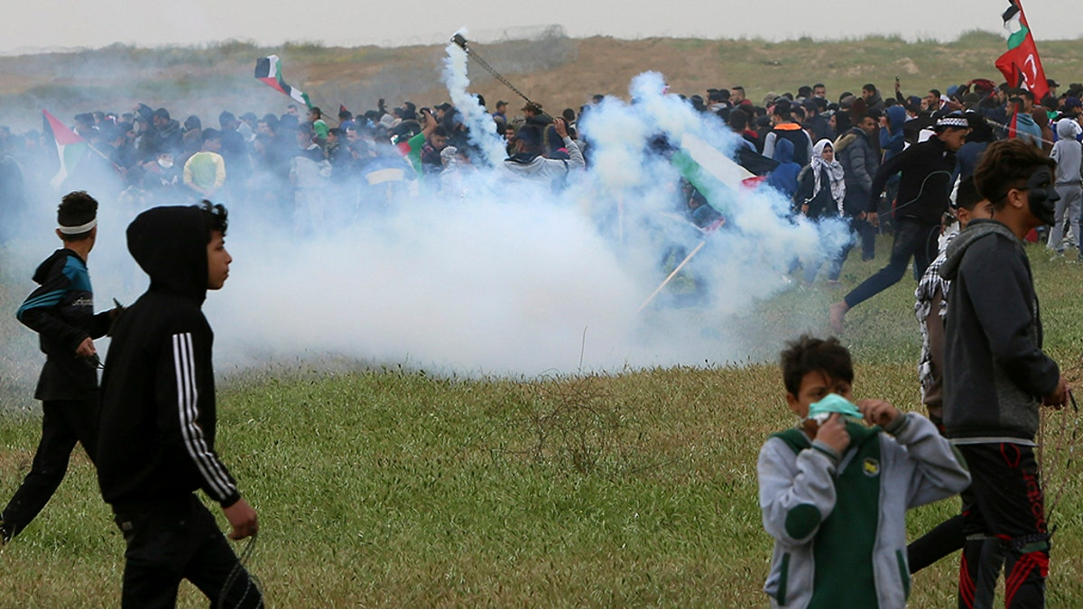 Protesters run for cover from teargas fired by Israeli troops near fence of Gaza Strip border with Israel, marking first anniversary of Gaza border protests east of Gaza City, Saturday, March 30, 2019. (AP Photo/Adel Hana)