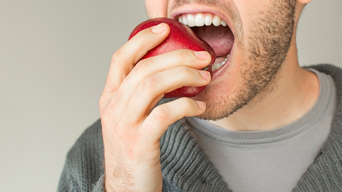 Man bites into red apple