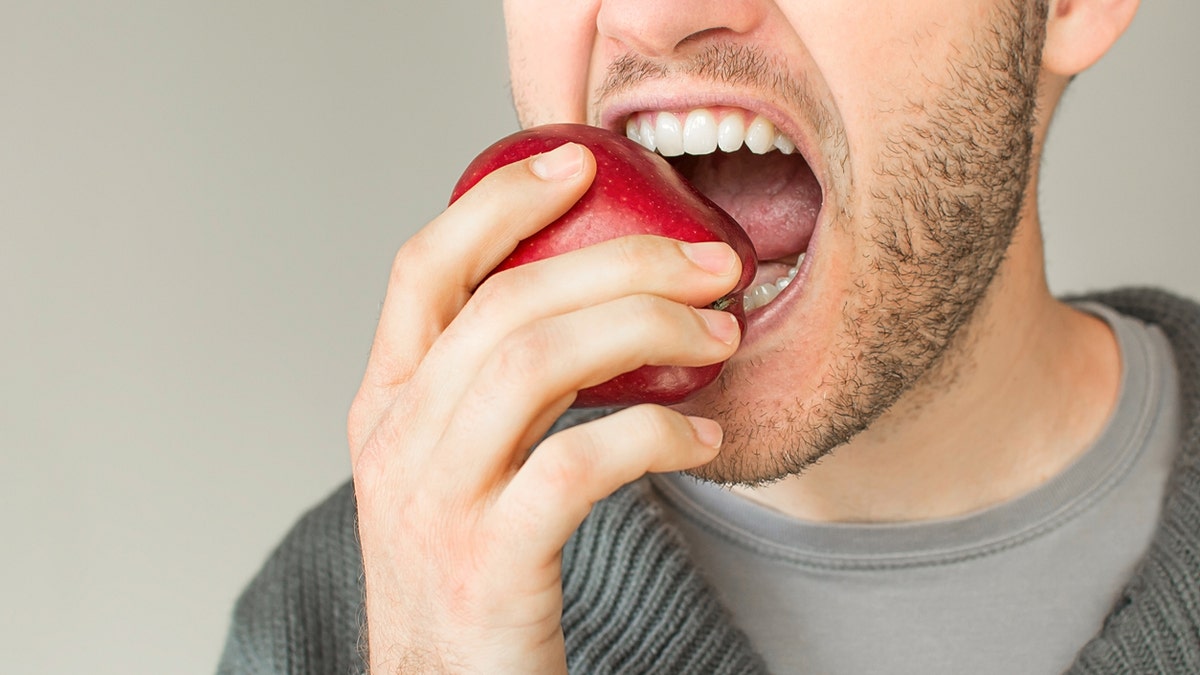 Man bites into red apple