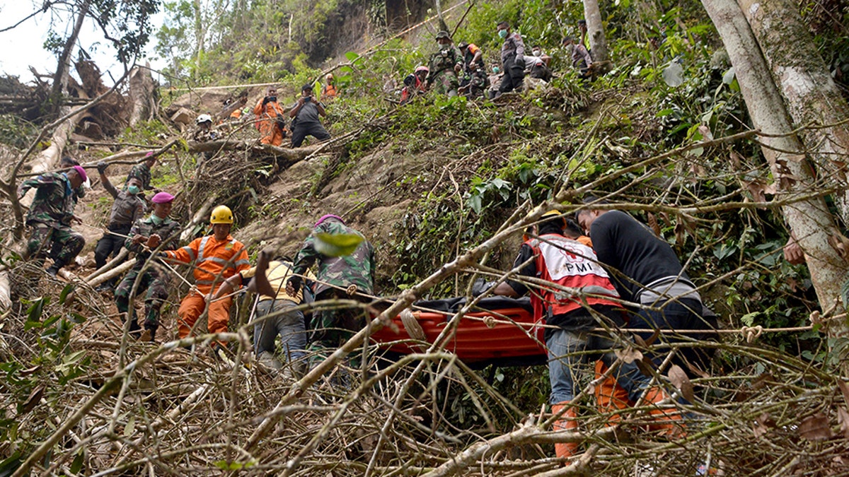 Rescuers carry a survivor of the collapsed mine on a stretcher through a steep terrain.