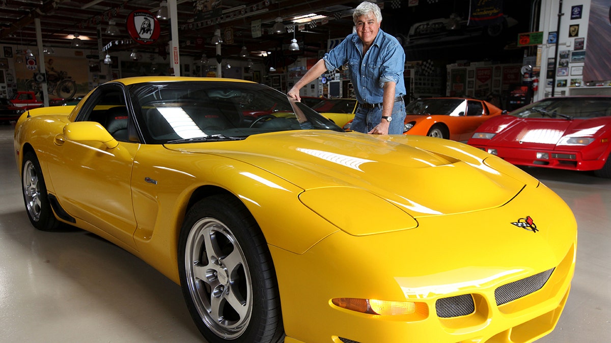 Jay Leno shows off a bright yellow car at his garage in Burbank