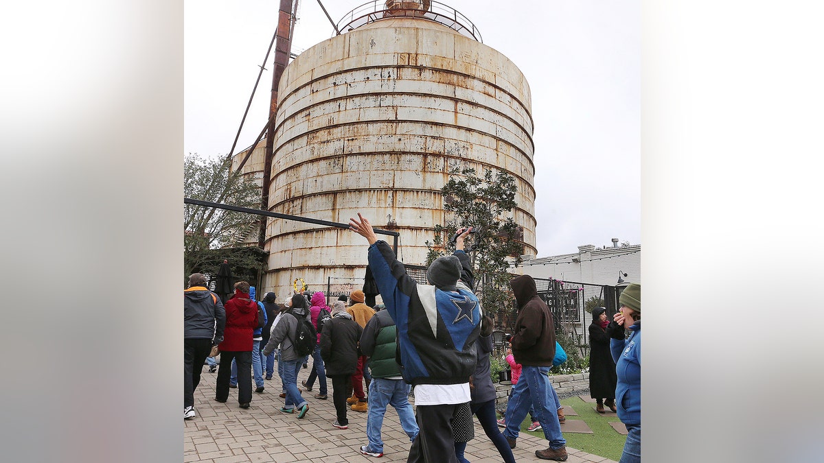 Church Under the Bridge members raise their arms while arriving at the new location at Magnolia Silos, Sunday, March 3, 2019, in Waco, Texas. The group had been meeting under the overpass at Interstate 35 but upcoming construction projects forced them to find the new location. Chip and Joanna Gaines offered them a temporary location at the Magnolia Market at the Silos. (Rod Aydelotte/Waco Tribune Herald via AP)