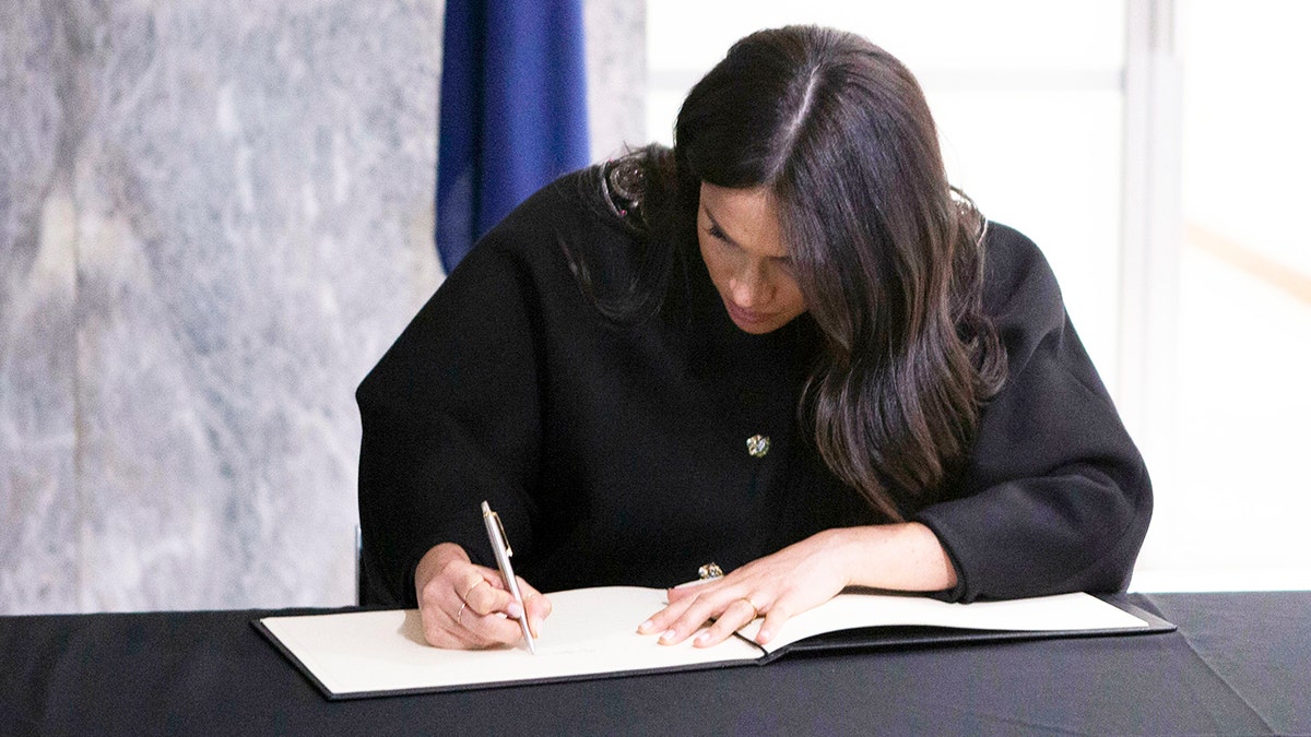 Britain's Meghan Duchess of Sussex signs the book of condolence, with Prince Harry, during a visit to the New Zealand High Commission in London, Tuesday March 19, 2019.  The royal couple visited New Zealand Commission following the Mosque terrorist shootings last week. (Ian Vogler/pool via AP)