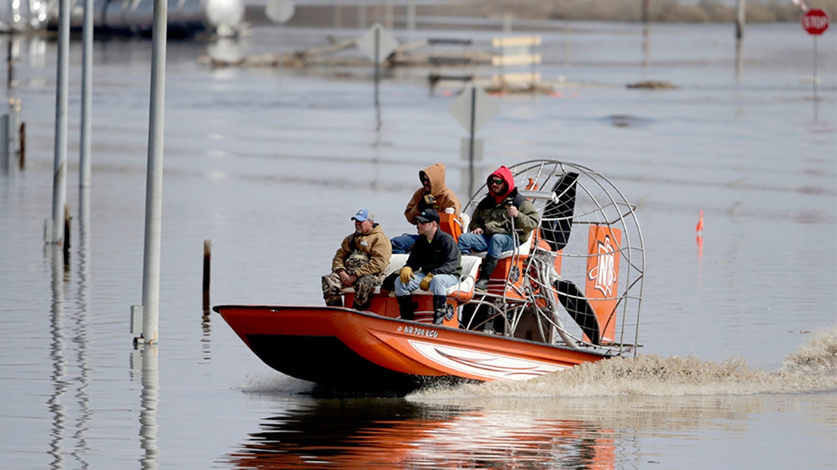 Gabe Schmidt, owner of Liquid Trucking, back right, travels by air boat with Glenn Wyles, top left, Mitch Snyder, bottom right, and Juan Jacobo, bottom left, as they survey damage from the flood waters of the Platte River, in Plattsmouth, Neb., on Sunday.