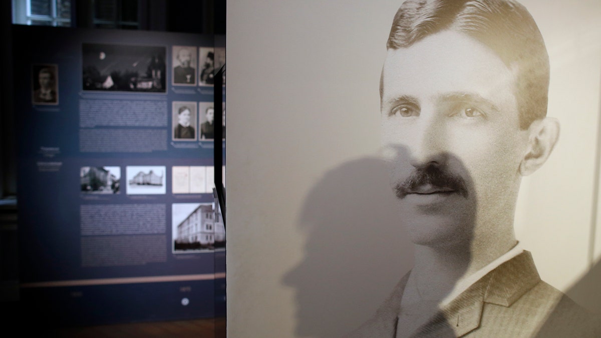 A shadow of Milica Kesler, curator and archivist is cast onto a poster of Nikola Tesla at the Nikola Tesla museum in Belgrade, Serbia, Thursday, March 7, 2019. A private culture society in Serbia has made public two letters written by Serb-American inventor and electricity pioneer Nikola Tesla. The Adligat group has told The Associated Press they recently obtained the letters from a collector and verified their authenticity with multiple sources. (AP Photo/Darko Vojinovic)