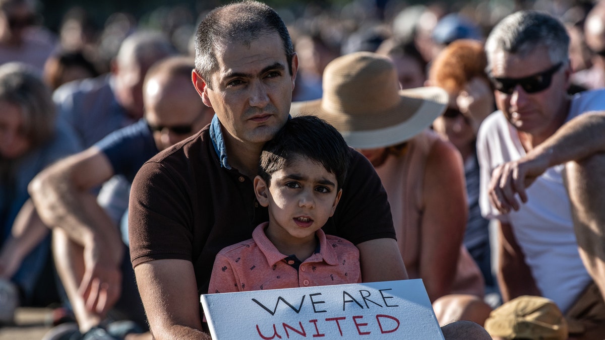 A young boy holds a placard as he takes part in a vigil to remember the victims of the Christchurch mosque attacks, on March 24, 2019, in Christchurch, New Zealand.?