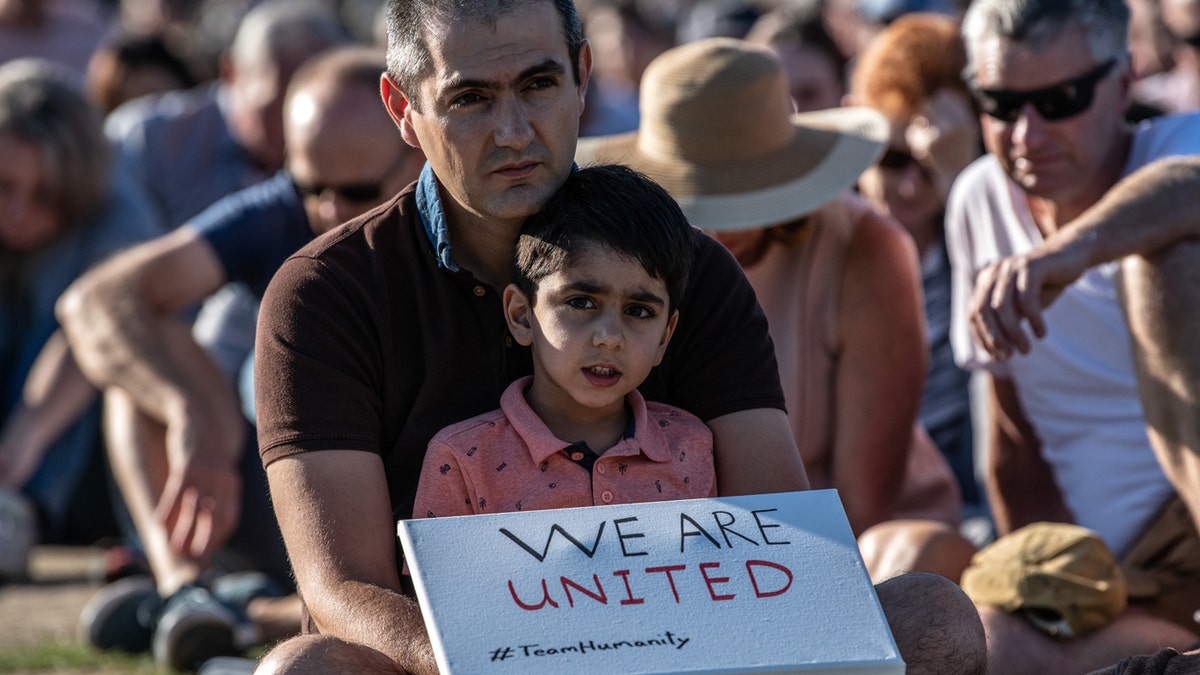 A young boy holds a placard as he takes part in a vigil to remember the victims of the Christchurch mosque attacks, on March 24, 2019, in Christchurch, New Zealand.