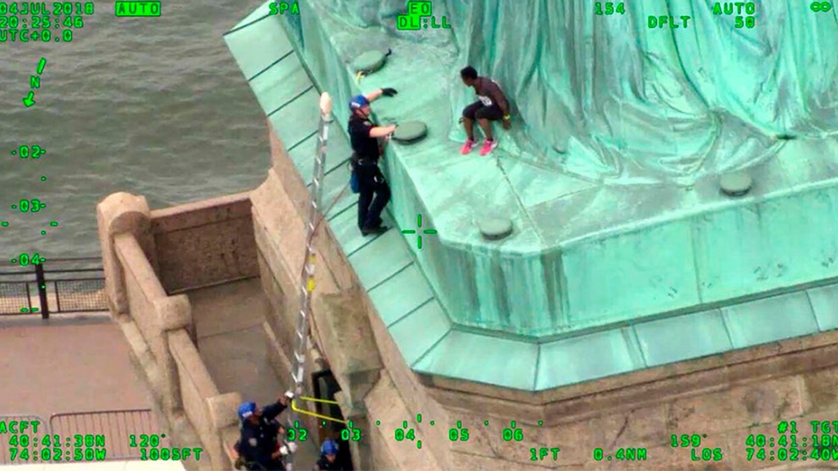 In this July 2018, frame from video provided by the New York City Police Department, members of the NYPD Emergency Service Unit work to safely remove Therese Okoumou, a protester who climbed onto the Statue of Liberty and was charged with misdemeanor trespassing and disorderly conduct. (AP/NYPD)