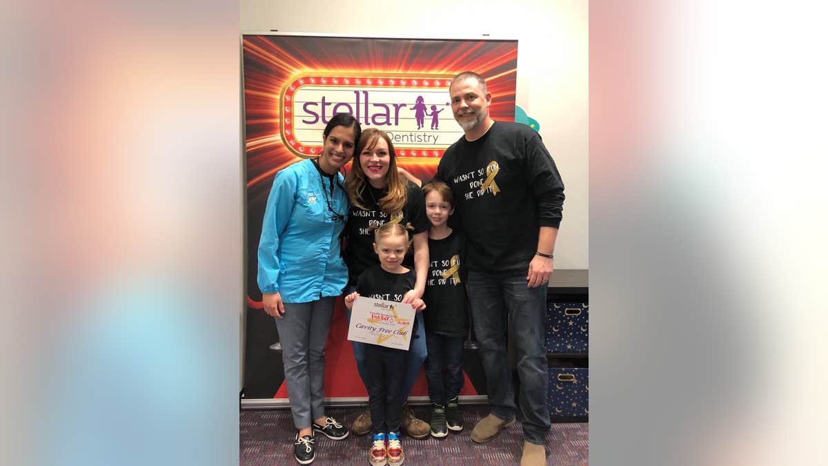 Hunter Jones, pictured holding her certificate, is now cancer-free after Dr. Harlyn Susarla, left, ordered a panoramic X-ray which revealed a growing tumor, and set-off 18 months of intense treatment to beat an aggressive cancer.