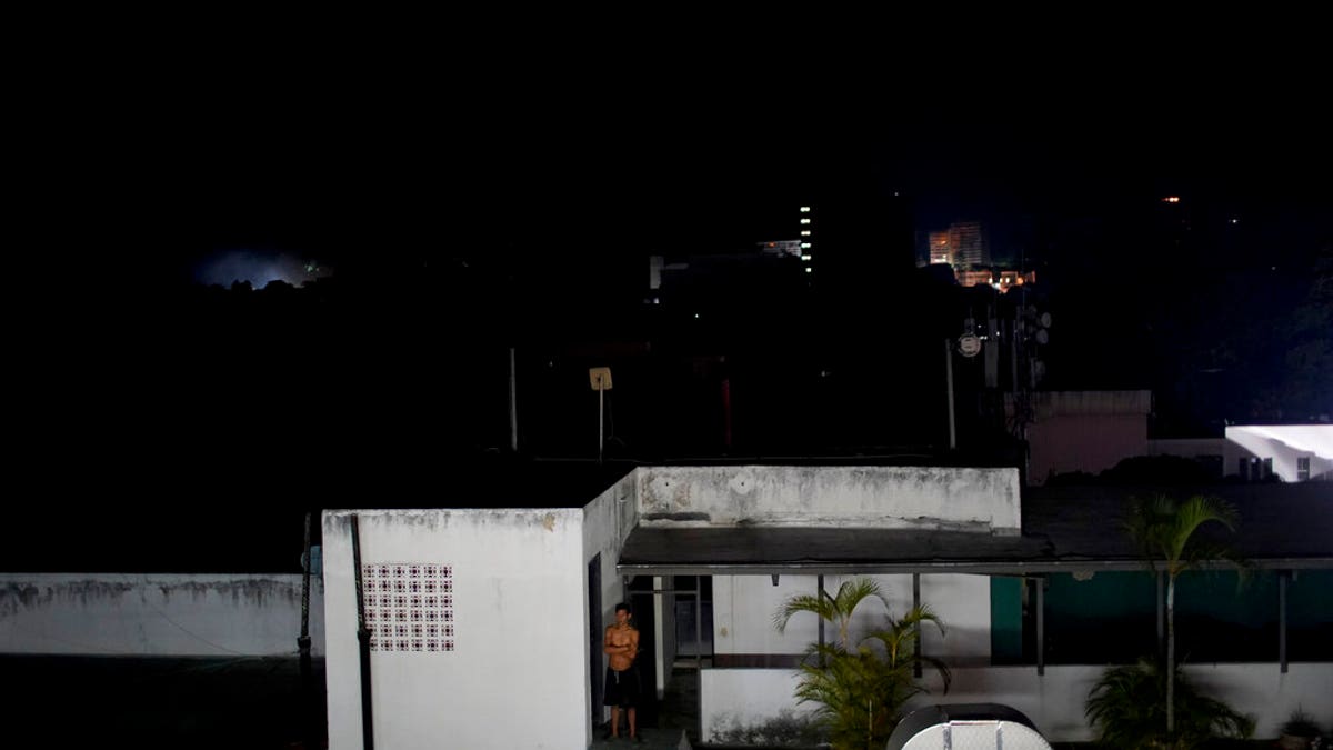 A man stands outside his home during a power outage in Caracas, Venezuela, Monday, March 25, 2019. A new power outage spread across much of Venezuela on Monday, knocking communications offline and stirring fears of a repeat of the chaos almost two weeks ago during the nation's largest-ever blackout.