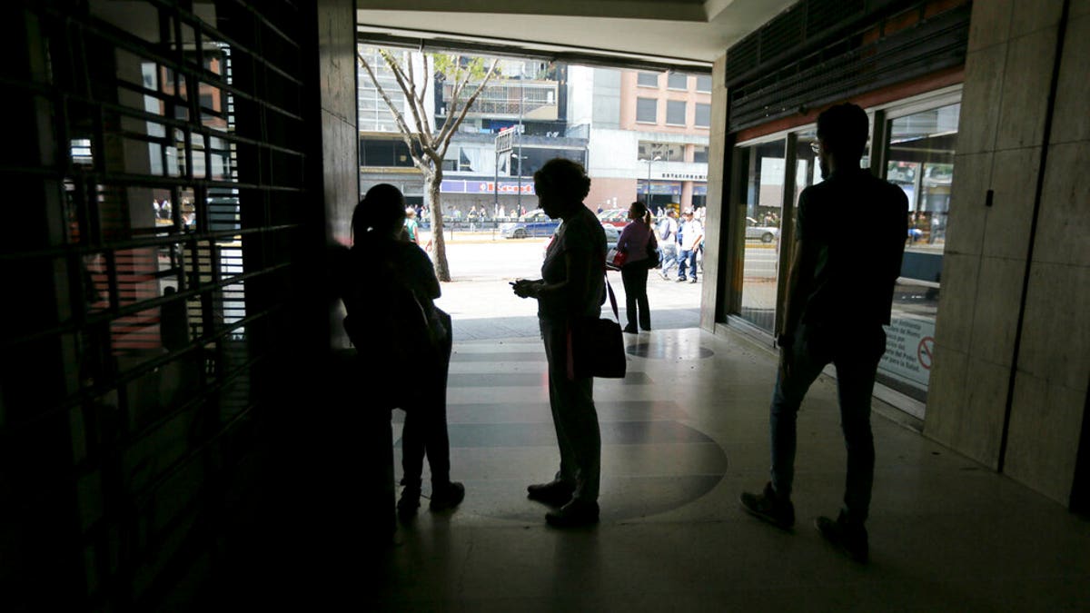 People wait inside a darkened office building during a power outage in Caracas, Venezuela, Monday, March 25, 2019. The subway suspended service because of the power cuts Monday, as local media reported outages in at least six states.