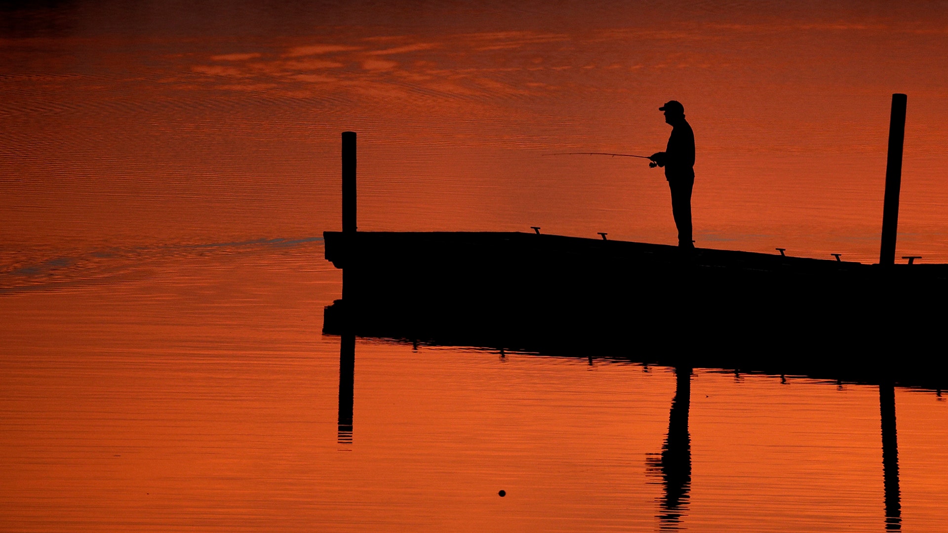 A man is silhouetted at dusk as he fishes on a dock at Shawnee Mission Park, in Lenexa, Kansas, March 11, 2019. 