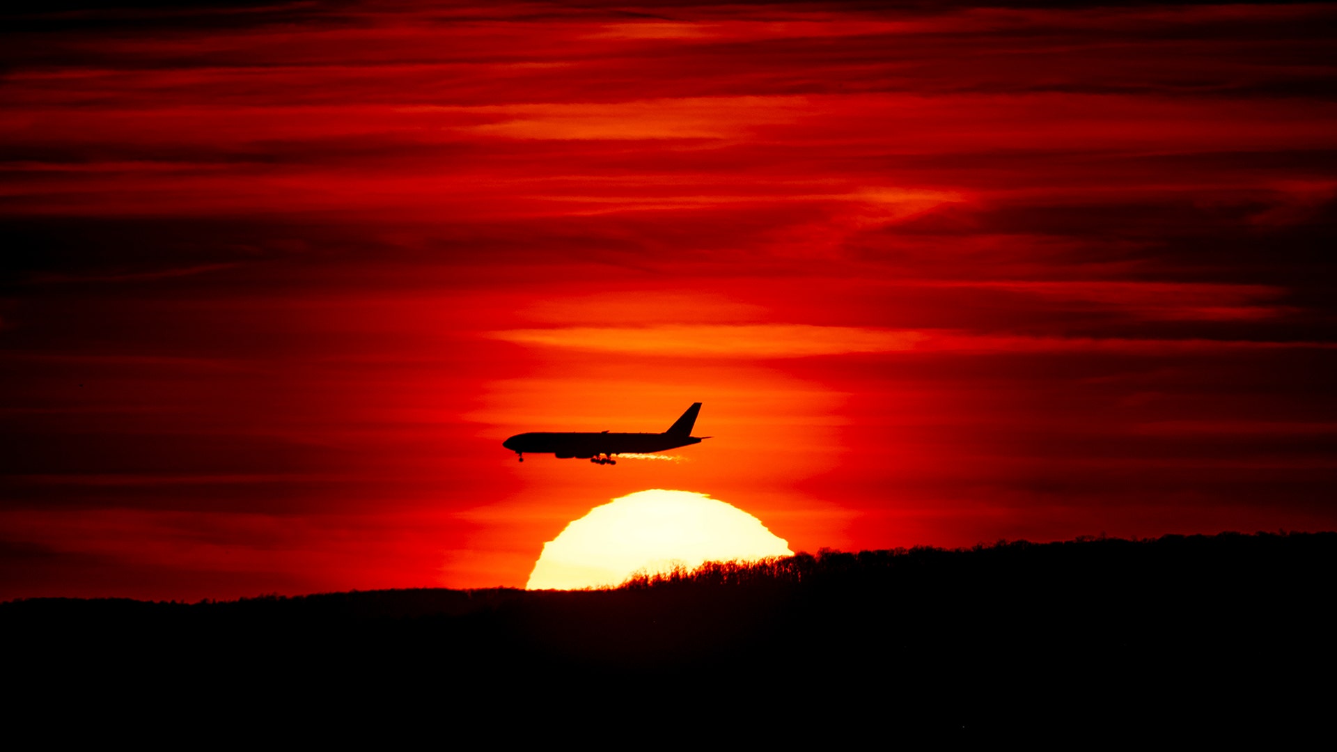 A passenger jet on approach to Newark Liberty International Airport flies over the setting sun in Newark, New Jersey, March 27, 2019.