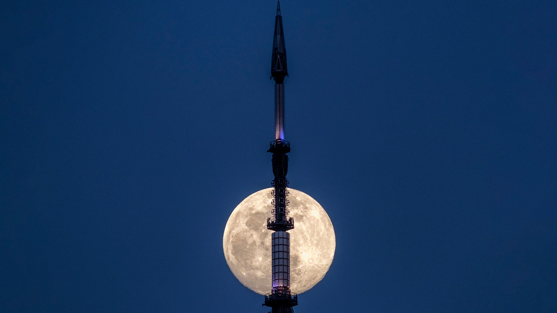 The rising moon passes behind the antenna on top of One World Trade Center in New York City, March 19, 2019.