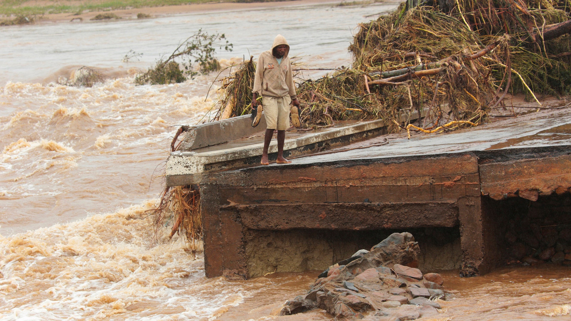 A man stands on the edge of a collapsed bridge in Chimanimani, about 600 kilometers southeast of Harare, Zimbabwe, March 18, 2019.