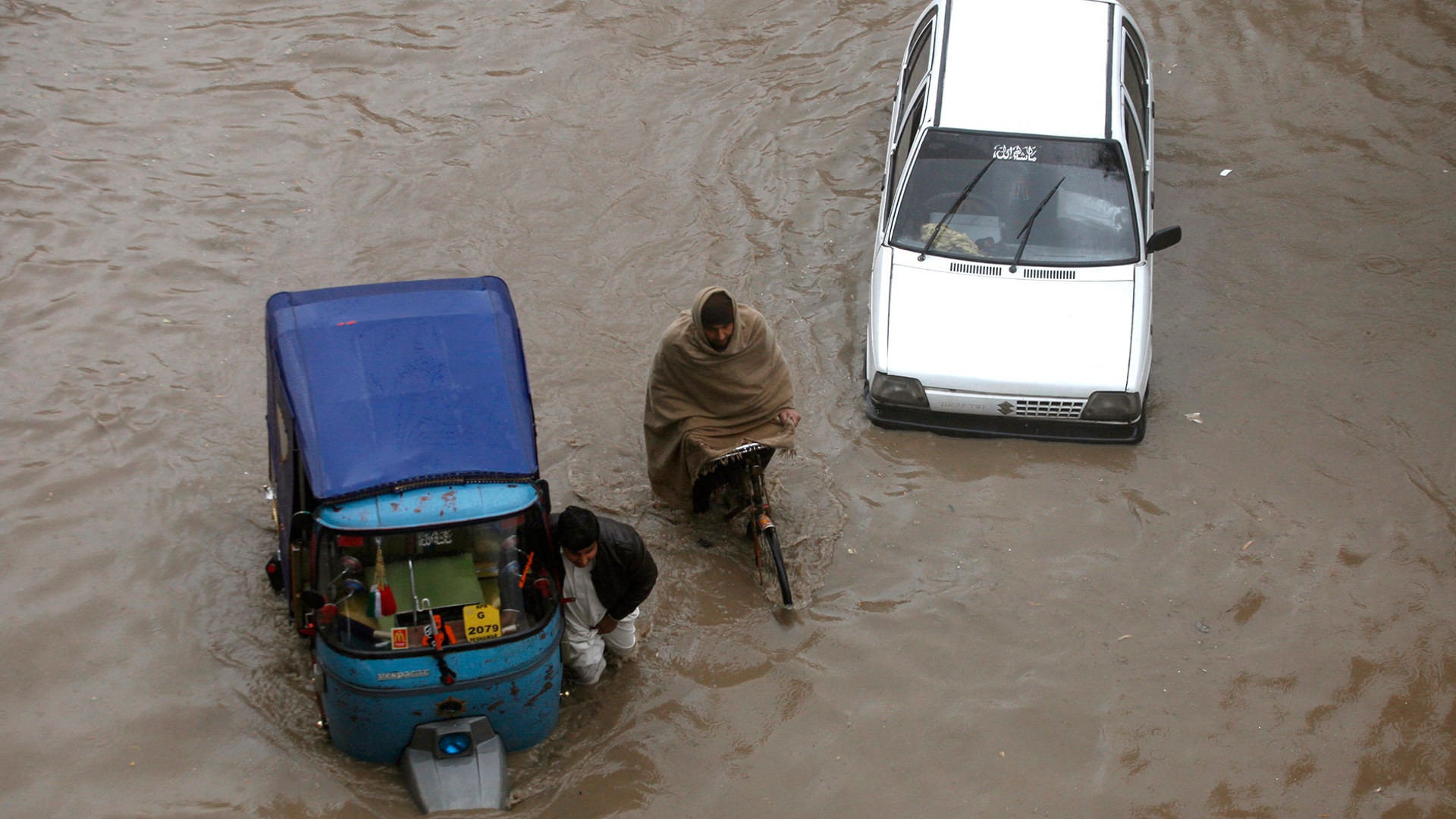 Pakistani commuters travel on a flooded street following heavy rainfall in Peshawar, Pakistan, March 11, 2019. 
