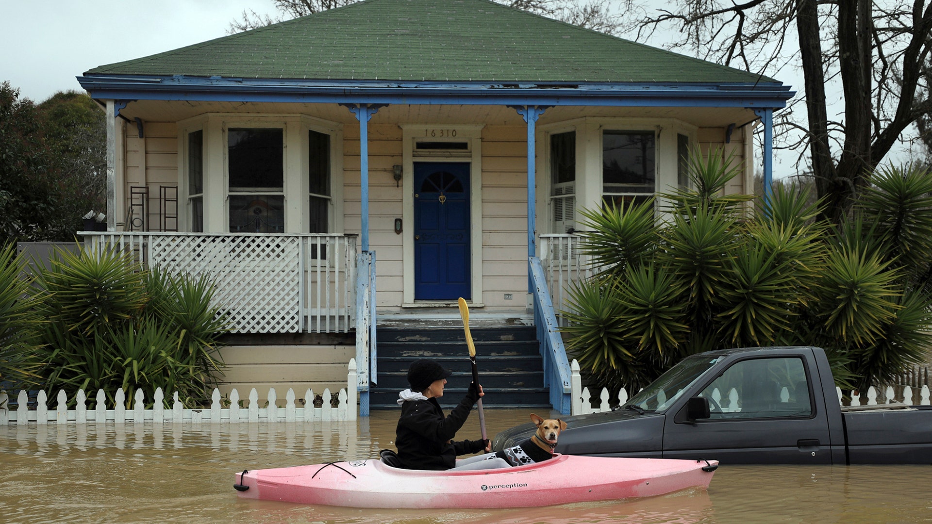 A woman with a dog sails a kayak on a flooded street in Guerneville, north of San Francisco, Feb. 27, 2019. 