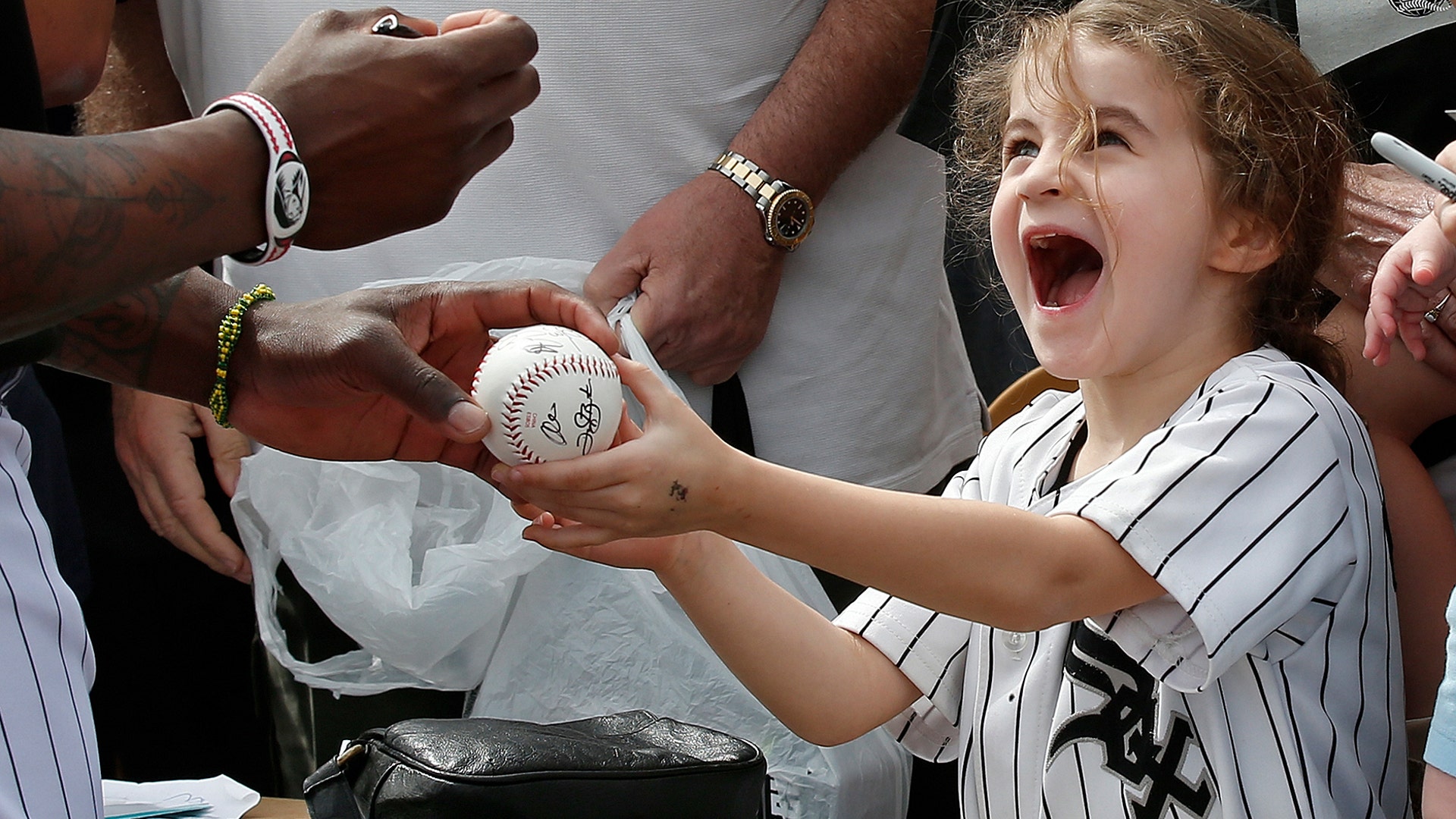 Six-year-old Joan Stiltner, of Chicago, holds a ball for Chicago White Sox left fielder Joel Booker to autograph before the team's spring training baseball game, in Glendale, Ariz., March 7, 2019. 