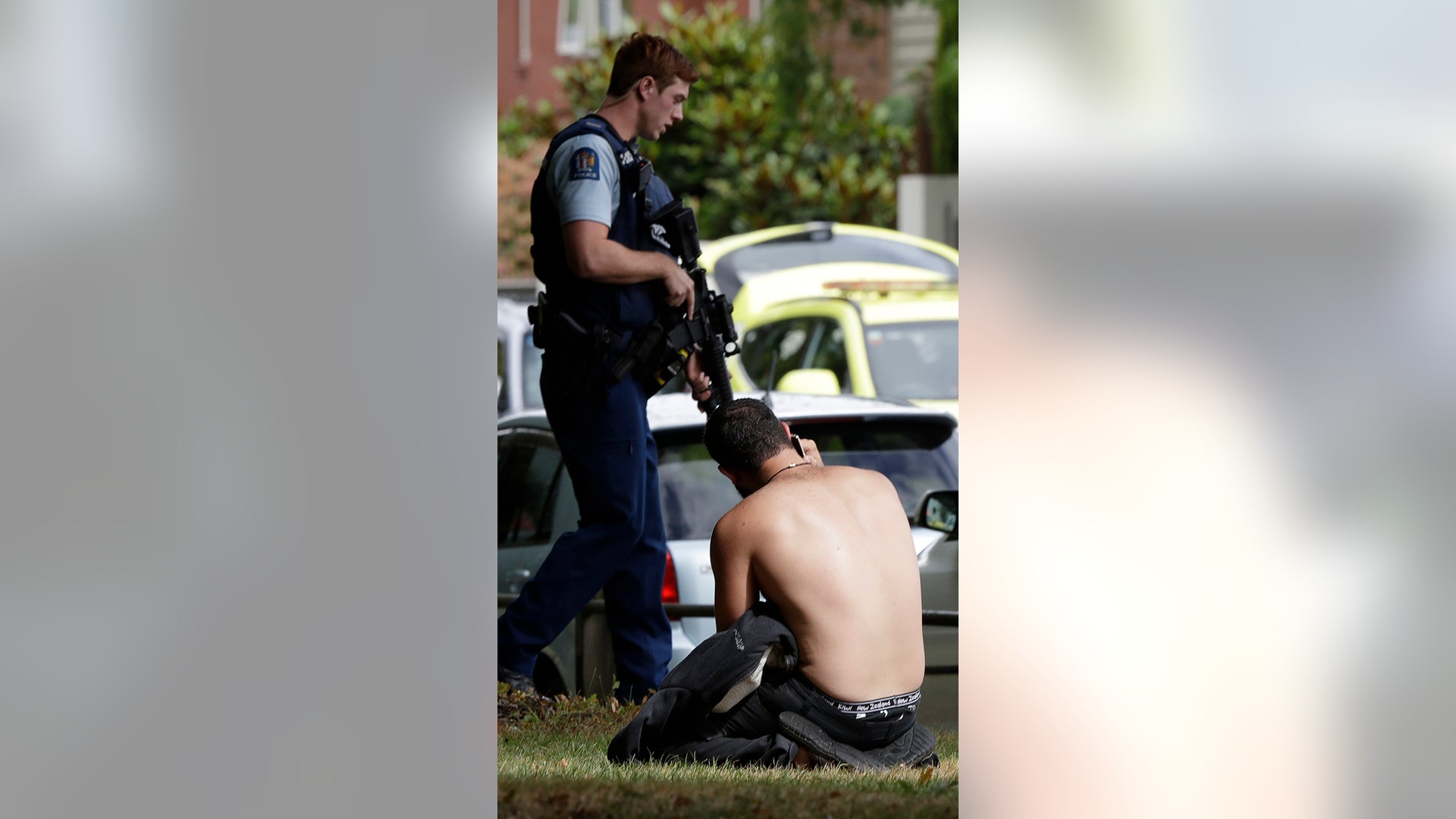 A man rests on the ground as he speaks on his mobile phone across the road from mosque in central Christchurch. (AP Photo/Mark Baker)
