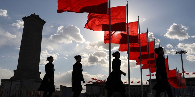 Bus ushers walk past red flags on Tiananmen Square during a plenary session of the Chinese People's Political Consultative Conference (CPPCC) at the Great Hall of the People in Beijing Monday, March 11, 2019 - file photo.