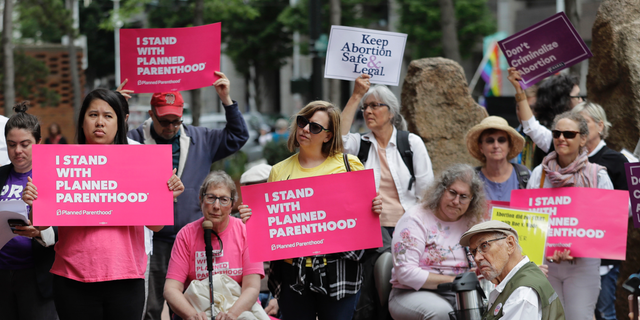In this July 10, 2018, photo, protesters hold signs supporting Planned Parenthood in Seattle and against Brett Kavanaugh's nomination to the Supreme Court.