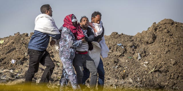 A grieving relative who lost his wife in the crash is helped by a member of security forces and others at the scene where the Ethiopian Airlines Boeing 737 Max 8 crashed shortly after takeoff on Sunday.