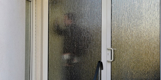 A customs officer passes behind a glass door of a house with a doctor's office during a doping raid in Erfurt, Germany on Wednesday, February 27, 2019. Several people were arrested during raids of Doping in Austria and Germany at the Nordic World Ski Championships.