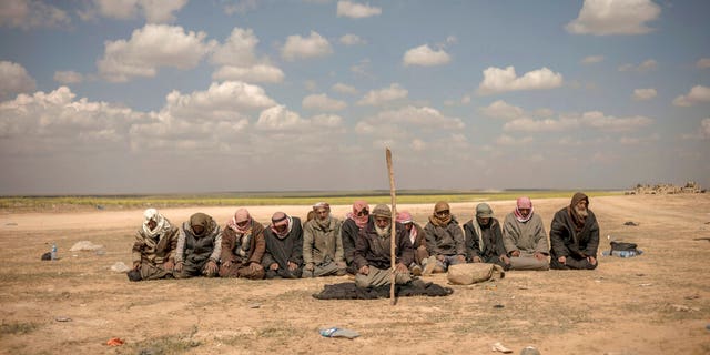 In this Wednesday photo, men pray at a reception area for people evacuated from the last shred of territory held by Islamic State militants, outside Baghouz, Syria.