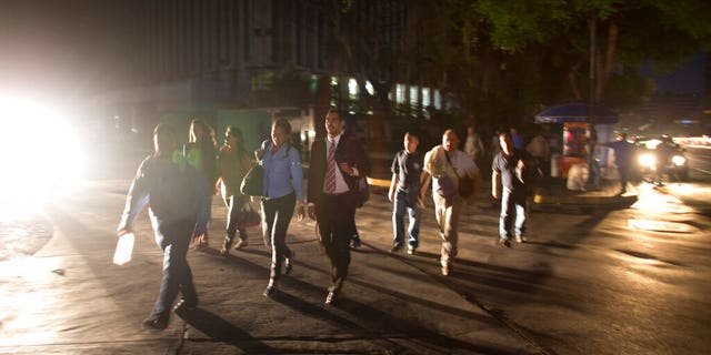 People walk on a dark street during a power outage in Caracas, Venezuela, Thursday, March 7, 2019. A power outage left much of Venezuela in the dark early Thursday evening in what appeared to be one of the largest blackouts yet in a country where power failures have become increasingly common.