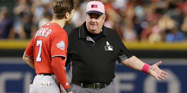 FILE - In this May 13, 2018, file photo, MLB umpire Joe West, right, talks with a player in the ninth inning during a baseball game between the Arizona Diamondbacks and the Washington Nationals in Phoenix. West, who has umpired more than 5,000 big league games, said the 2016 TrackMan computer system test was far from perfect.