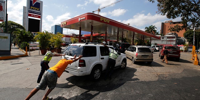 People push a car without fuel to one of the few gas stations that has its own electric generator during an electricity blackout in Caracas, Venezuela, Sunday, March 10, 2019. Power and communications outages continue to hit Venezuela, intensifying the hardship of a country paralyzed by economic and political crisis and heightening tension between the bitterly divided factions which accuse each other of being responsible for the collapse of the power grid. (AP Photo/Eduardo Verdugo)