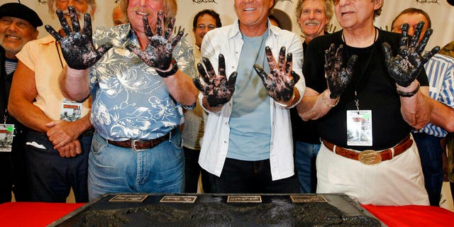 FILE: Don Randi, from left, Glen Campbell and Hal Blaine, representing session musicians known as The Wrecking Crew, hold up their hands after placing them in the cement following the induction ceremony for Hollywood's RockWalk in Los Angeles.
