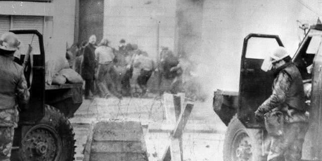 In this Jan. 30, 1972 file photo, soldiers take cover behind their sandbagged armored cars in Londonderry, Northern Ireland.