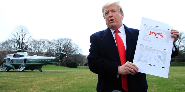 President Donald Trump shows a map of Syria and Iraq showing the presence of the Islamic State in 2017 and 2019, as he speaks to reporters before leaving the White House in Washington, Wednesday, March 20, 2019, for a trip to visit an Army tank plant in Lima, Ohio, and a fundraising event in Canton, Ohio. (AP Photo/Manuel Balce Ceneta)
