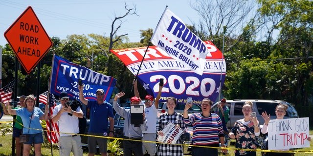 People with signs supporting President Trump are seen from the media van in the motorcade accompanying the president in West Palm Beach, Fla., Friday. (AP Photo/Carolyn Kaster)