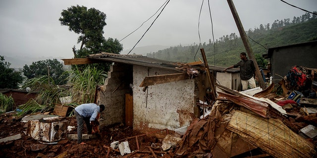 Men search to salvage what they can from a house which was damaged by Cyclone Idai in Chimanimani, Zimbabwe, Saturday, March 23, 2019 after Cyclone Idai caused floods that swept through Mozambique, Zimbabwe and Malawi. A second week has begun of efforts to find and help some tens of thousands of people in devastated parts of southern Africa, with some hundreds dead and an unknown number of people still missing.(AP Photo/KB Mpofu)