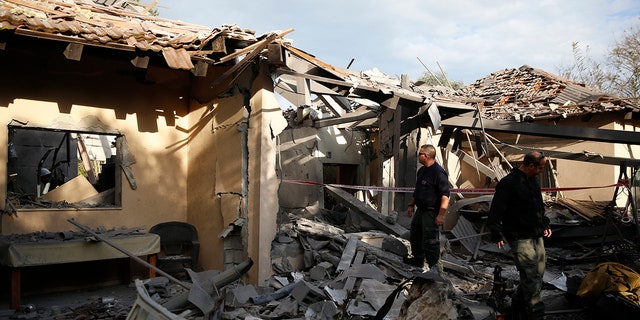 Police officers inspect the damage to a house hit by a rocket in Mishmeret, central Israel, Monday, March 25, 2019. An early morning rocket from the Gaza Strip struck a house in central Israel on Monday, wounding six people, including one moderately, an Israeli rescue service said, in an eruption of violence that could set off another round of violence shortly before the Israeli election. (AP Photo/Ariel Schalit)